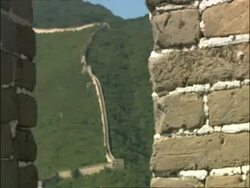 Pan right from bricks, through battlements, to Great Wall of China snaking up hill, Mutianyu, China Stock Footage
