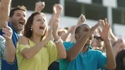 Stadium crowd cheers at sporting event, rises to feet; woman high-fives Stock Footage