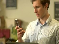 MS, Wine shop clerk using mobile phone, customer waiting at counter, Soho, New York City, New York, USA Stock Footage