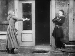 B/W 1917 policeman Charlie Chaplin climbing from manhole to street + greeting woman / he falls down Stock Footage