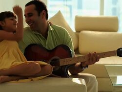 Man playing a guitar with his daughter  Stock Footage