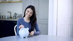 Happy woman inserting coins into her piggy bank Stock Footage