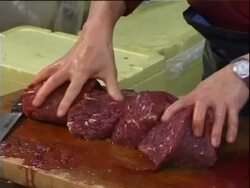 Tsukiji fish market, Tokyo, Japan, MS man slicing whale meat on chopping board . Stock Footage