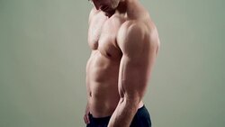 beautiful athlete trains with a dumbbell on a grey background Stock Footage