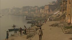 Rowboats moor at the foot of a temple where pedestrians pass in India. Stock Footage