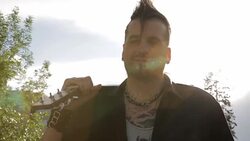 Cool young man with mohawk holding guitar over shoulder in sunny city Stock Footage