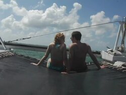 MS, Cayman Islands, Grand Cayman, Stingray City, Young couple sitting in front of catamaran in sea, rear view Stock Footage