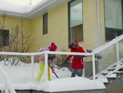 Mother and daughter shoveling snow off house deck and steps Stock Footage