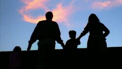 A family holds hands while walking up a hill. Stock Footage
