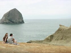 WS PAN Couple sitting on cliff with sea in background / Cape Kiwanda, Oregon, USA Stock Footage
