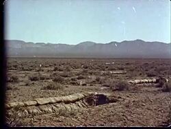 1950s WS Desert and mountains in background / Trenches lined with sandbags / Light flashing from atomic explosion at Camp Desert Rock at Nevada Test Site / Nye County, Nevada, USA Stock Footage