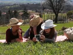 Three teens look at camera phone in green field playfully Stock Footage