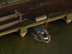 Aerial of tour boat passing under railway bridge on Thames / pull out to view of Thames / London Stock Footage