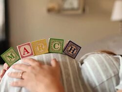 A pregnant women using blocks to spell the month of MARCH on her stomach. Stock Footage