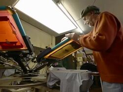 MS LA View of an artisian pulling ink over a silk screen to print designs on a shirt / Ann Arbor, Michigan, United States Stock Footage