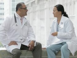 MS PAN Two physicians sitting on bench in hospital corridor talking / Seattle, Washington, USA Stock Footage