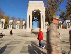 A static shot of a group of soldiers walking in front of the World War II Memorial. Stock Footage