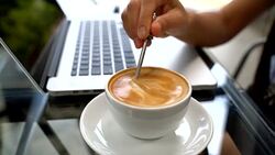 Closeup of Latte Coffee art and woman hand typing on laptop keyboard Stock Footage