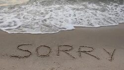 'Sorry' word written on the sand Stock Footage