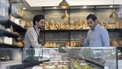 Customer looking at options in the bakery and salesman serving Stock Footage