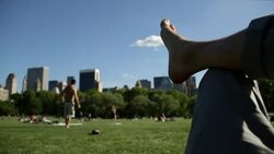 POV of man in the park with people throwing a football in the background at Central Park Stock Footage
