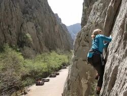 Woman climbs steep rock cliff in canyon, leading Stock Footage