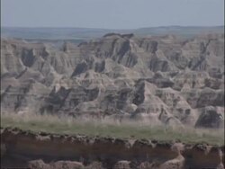 MS long pan left across jagged rocky landscape with grassy patches stretching to hazy horizon, blue sky, USA Stock Footage