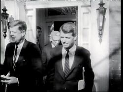 John F. Kennedy and Robert F. Kennedy stand in front of John's house talking to reporters. News Clip
