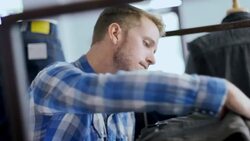 Young employee counts pants on shelf and types on tablet in modern clothing store Stock Footage