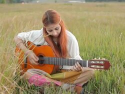 Hippie girl playing guitar on grass Stock Footage
