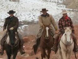 MS Two cowboys and a cowgirl riding horses with their dogs and snow in the background / Shell, Wyoming, United States Stock Footage