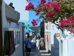 MS Shot of Oia Cyclades white buildings and steep mountains Greek Islands beautiful peaceful place with walking tourists / Santorini, Greece Stock Footage
