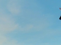 Wide shot young blonde woman in mask, cape, and superhero costume in midair simulating flying after jumping on trampoline Stock Footage