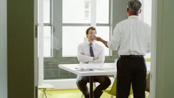 MS Smiling businessman in discussion with colleague standing at conference room table Stock Footage