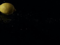 Lemon single falling into water, black background Stock Footage