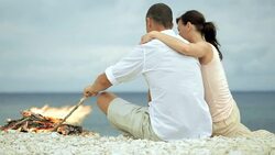 Lovely couple hugging and talking on the beach by fire Stock Footage