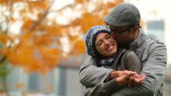 Young man in love wraps arms around and kisses girlfriend in autumn park Stock Footage