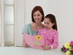 Girl giving mothers day card and flowers to mother Stock Footage