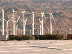 PAN with freight train across solar photovoltaic power plant next to wind farm and interstate highway traffic  / Palm Springs, California, USA Stock Footage