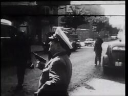 B/W 1961 man in uniform holding gun standing in street looking up / West Berlin / Germany Stock Footage