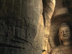 MS TU Shot of smaller Buddha sutra carving figure and much larger one next to it in cave at Yungang Grottoes / Datong, Shanxi Province, China Stock Footage