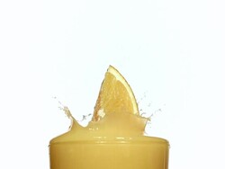 CU SLO MO Orange segment falling into glass of orange Juice and juice splashing / Vieux, Normandy, France  Stock Footage