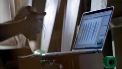 Shop owner works on laptop and hangs price tags on new longboards Stock Footage