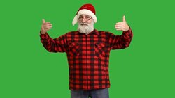 adult senior beard man showing an copy space and showing a thumb  in a hat santa claus  on a green background Stock Footage