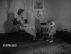 1953: TWO YEAR OLD: Girl standing near seated mother, slipping dress up onto shoulders (dress now in proper direction), looking at decoration on front of dress. Instructional Video