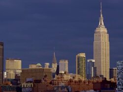 Shot of the Midtown Manhattan Skyline against a clear deep blue sky. The Empire State Building and the Chrysler Building are in the center of the shot along with the rest of the skyline and the harbor Stock Footage