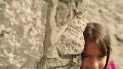 Cute young hispanic girl smiles at camera on third-world street corner Stock Footage