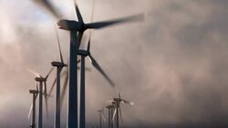 A cluster of wind turbines spins against  gray clouds. Stock Footage