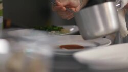 Chef spoons steaming sauce on clean dinner plate in restaurant kitchen Stock Footage