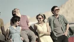 Friends lean on classic red convertible and laugh Stock Footage